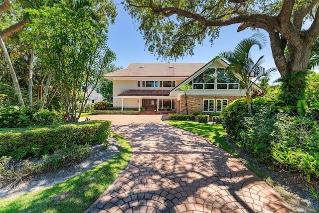 view of front of home with decorative driveway, brick siding, and stucco siding