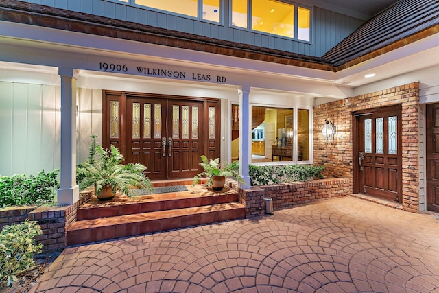 property entrance featuring brick siding, covered porch, and french doors