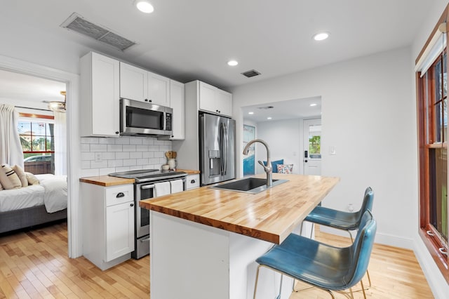 kitchen with a kitchen bar, sink, butcher block countertops, and stainless steel appliances