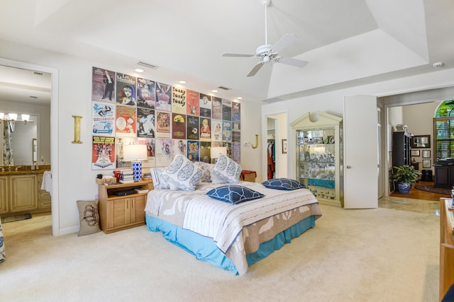 carpeted bedroom with ceiling fan, connected bathroom, and a tray ceiling