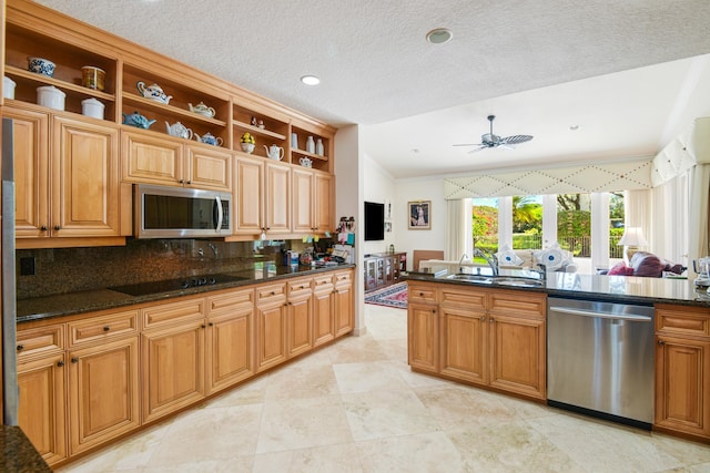 kitchen with sink, stainless steel appliances, dark stone counters, and tasteful backsplash