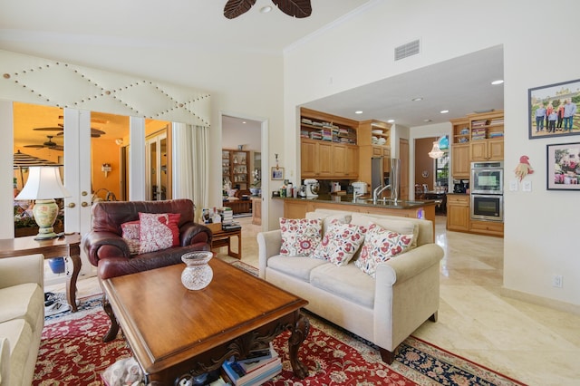 living room featuring ceiling fan, light tile patterned flooring, ornamental molding, and sink