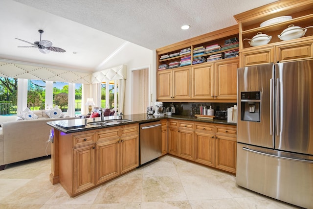 kitchen with kitchen peninsula, ceiling fan, appliances with stainless steel finishes, vaulted ceiling, and sink