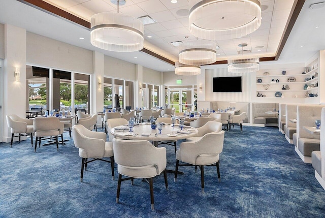 carpeted dining area with built in shelves and a raised ceiling