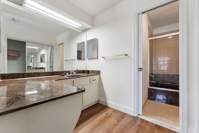 bathroom featuring hardwood / wood-style floors, vanity, and a tile shower