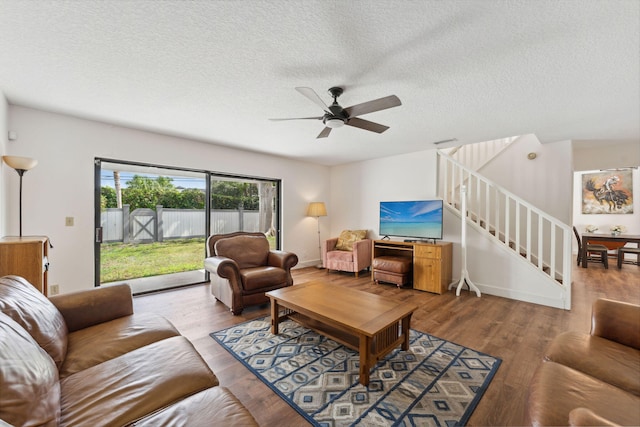 living room with ceiling fan, wood-type flooring, and a textured ceiling