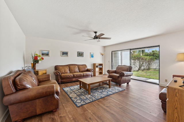 living room with hardwood / wood-style flooring, ceiling fan, and a textured ceiling