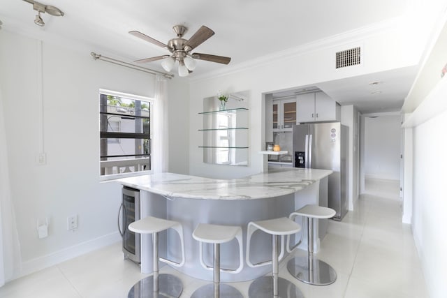 900 Euclid Ave Unit 8, Miami Beach, FL 33139 - kitchen with stainless steel fridge, a breakfast bar area, beverage cooler, crown molding, and light stone counters