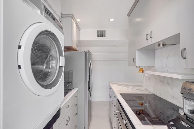 kitchen featuring stainless steel fridge, black electric cooktop, light tile patterned floors, white cabinets, and washer / dryer