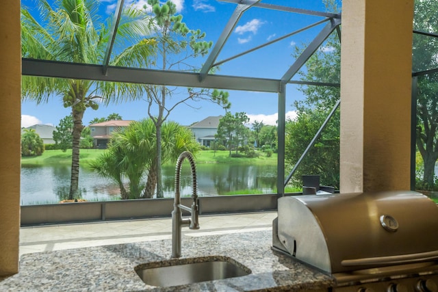 interior space featuring glass enclosure, a grill, a water view, and sink