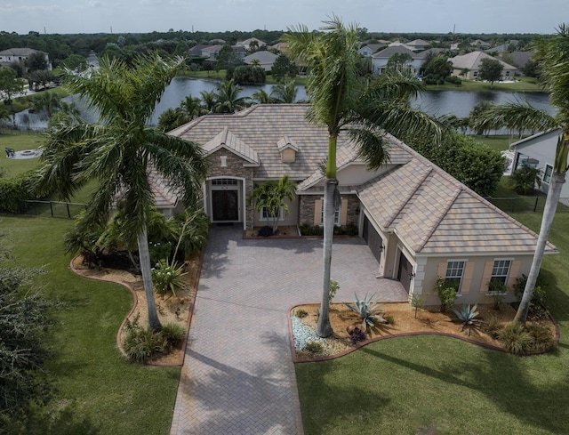 view of front of house with a garage, a water view, and a front lawn