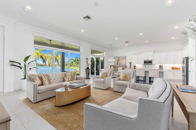 tiled living room featuring ceiling fan with notable chandelier, french doors, crown molding, and a water view