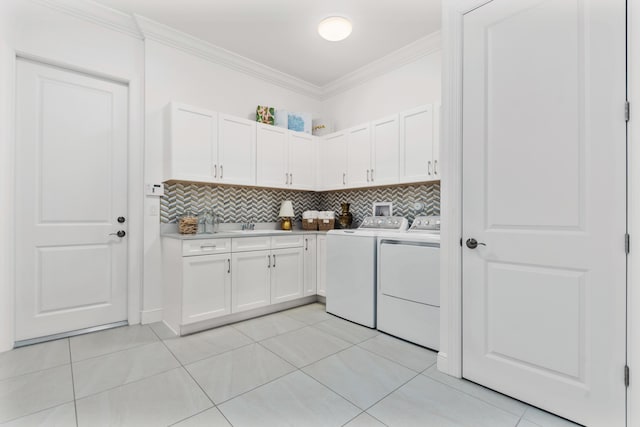 clothes washing area with washer and dryer, ornamental molding, light tile patterned floors, and cabinets