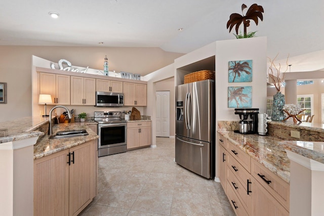 kitchen featuring light stone countertops, stainless steel appliances, and light brown cabinetry