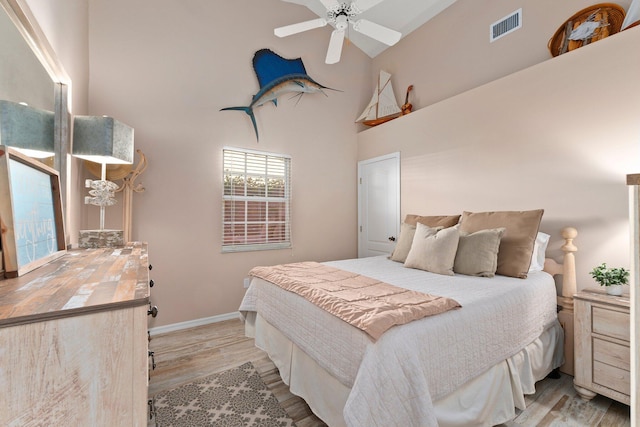 bedroom with ceiling fan, light hardwood / wood-style floors, and high vaulted ceiling