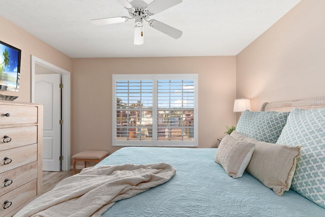 bedroom with ceiling fan, light hardwood / wood-style flooring, and a textured ceiling