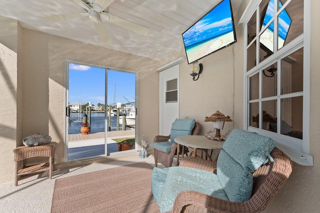 sunroom / solarium with ceiling fan and a water view