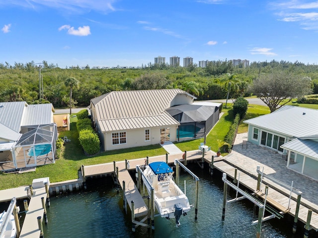 dock area with a lanai, a yard, a water view, and a pool