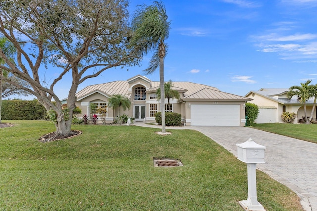 single story home featuring french doors, a front lawn, and a garage