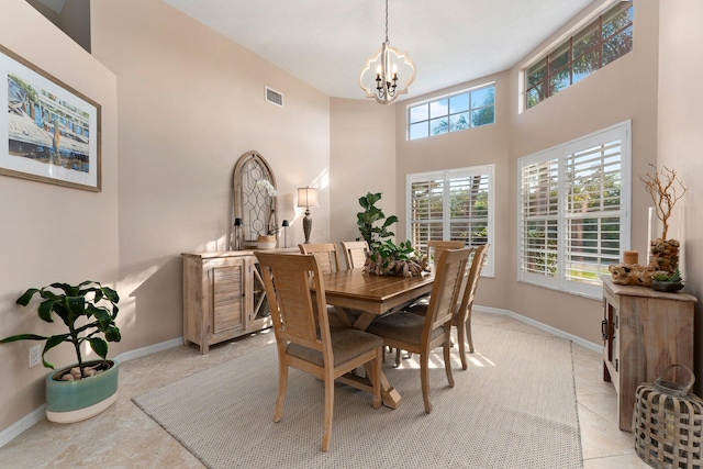 dining room with a notable chandelier, light tile patterned floors, and a towering ceiling