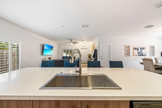 kitchen with an island with sink, stainless steel dishwasher, ceiling fan, and sink