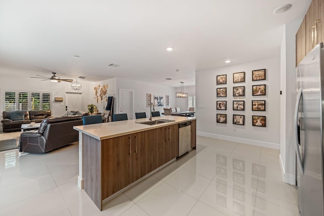 kitchen with ceiling fan, sink, a kitchen island with sink, light tile patterned floors, and appliances with stainless steel finishes