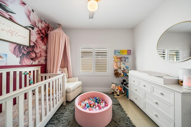 tiled bedroom featuring ceiling fan and a nursery area