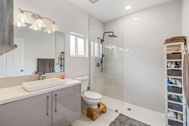 bathroom with tile patterned flooring, a tile shower, vanity, and toilet