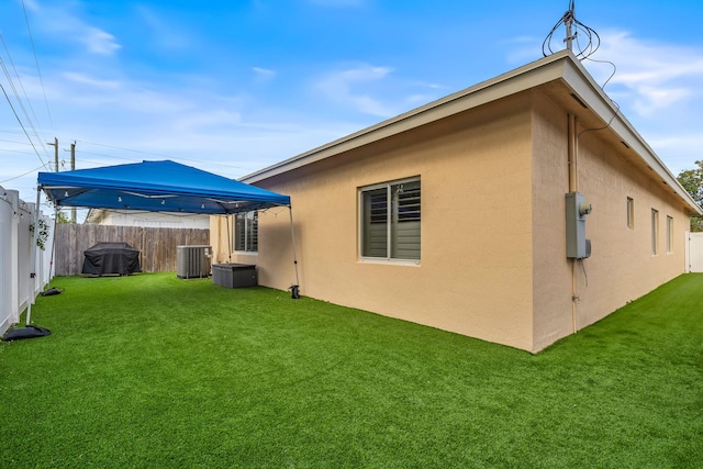 rear view of house featuring a yard and central AC