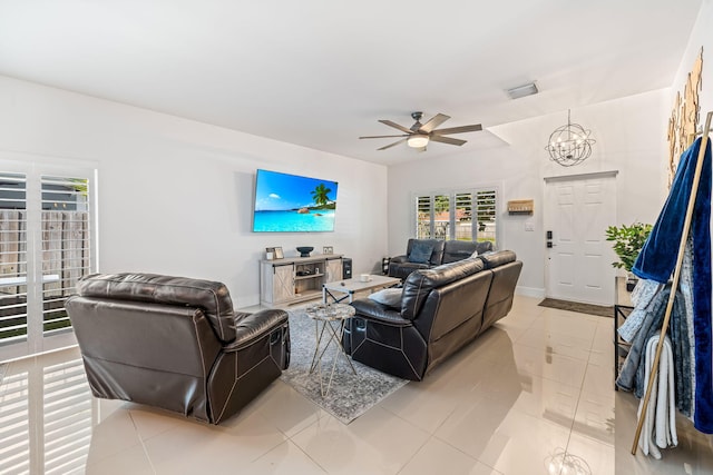 tiled living room featuring ceiling fan with notable chandelier