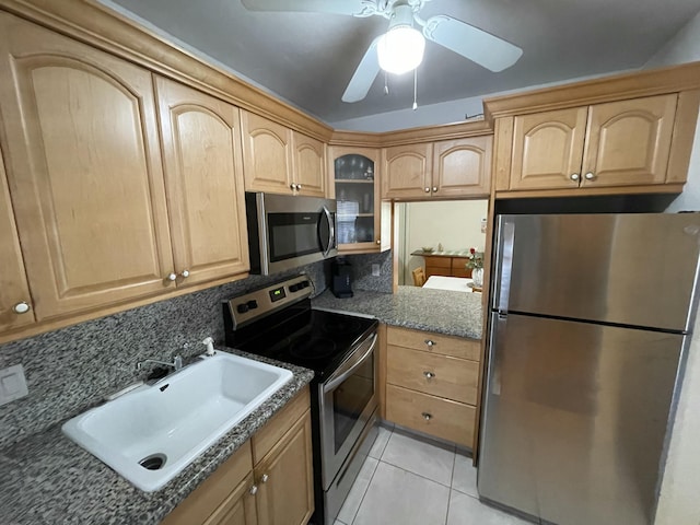 kitchen featuring light tile patterned floors, stainless steel appliances, tasteful backsplash, dark stone counters, and sink