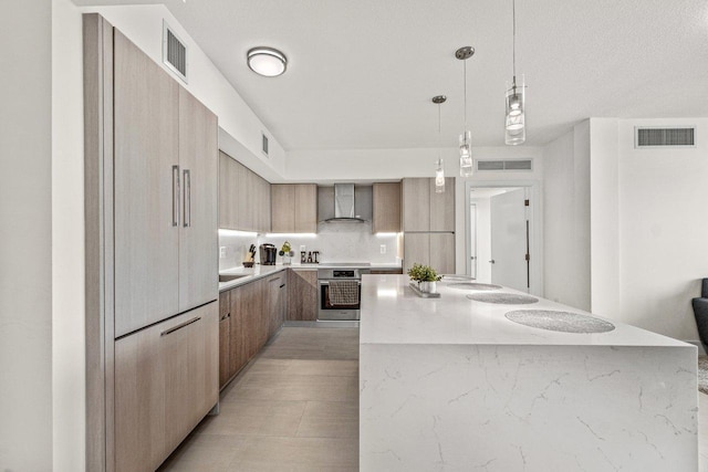 kitchen with oven, paneled fridge, hanging light fixtures, a kitchen island, and wall chimney range hood