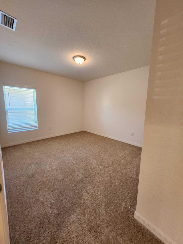 empty room featuring dark carpet and a textured ceiling