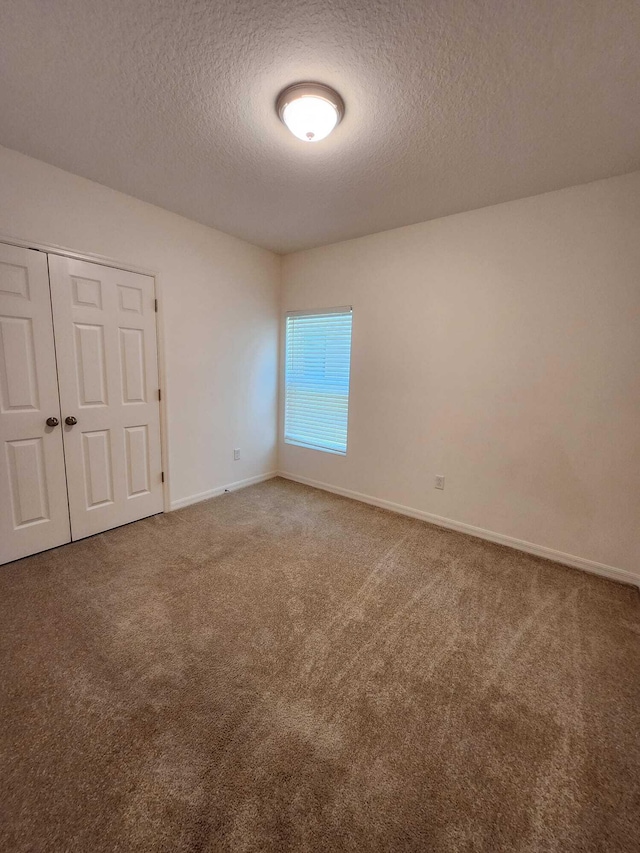 carpeted empty room with a textured ceiling