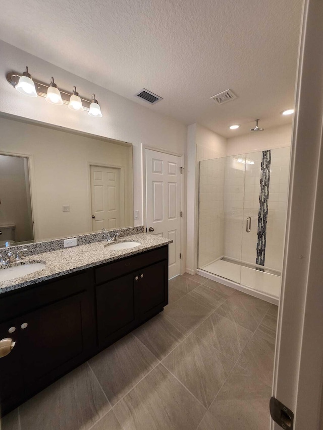 bathroom with vanity, a shower with shower door, tile patterned floors, and a textured ceiling