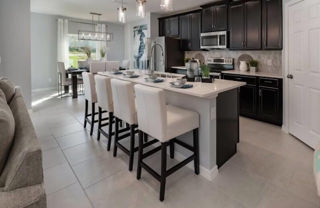 kitchen with pendant lighting, an island with sink, sink, a kitchen bar, and stainless steel appliances