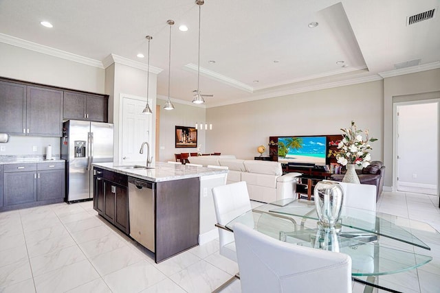 kitchen featuring appliances with stainless steel finishes, dark brown cabinetry, sink, a center island with sink, and hanging light fixtures