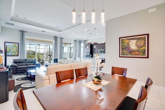 tiled dining area with a tray ceiling and ornamental molding