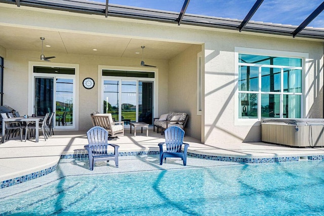 view of swimming pool featuring glass enclosure, ceiling fan, an outdoor living space, a hot tub, and a patio