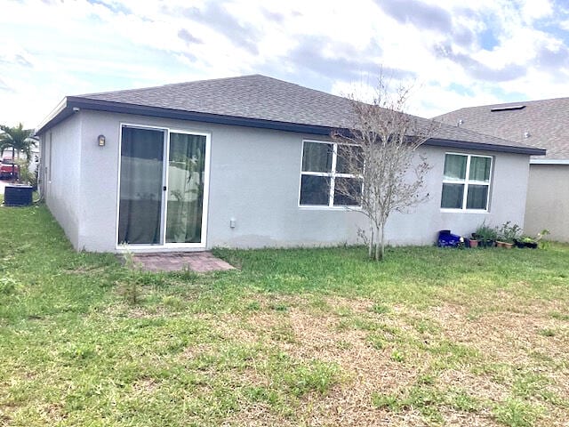 back of property featuring central AC unit and a lawn