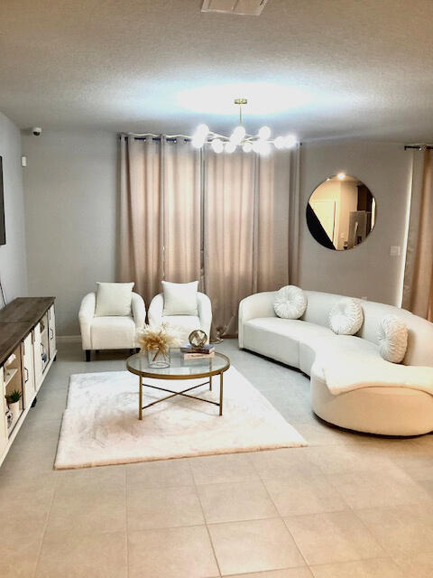 tiled living room featuring a textured ceiling and an inviting chandelier