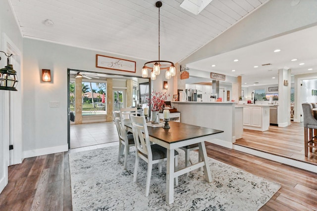 dining space featuring lofted ceiling with skylight, sink, ceiling fan, wood ceiling, and light hardwood / wood-style floors