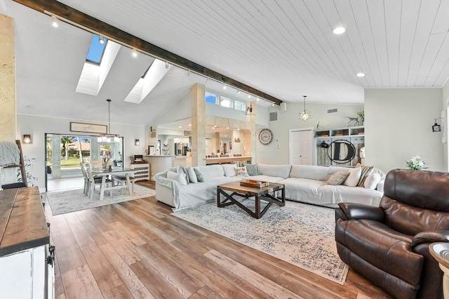 living room with a skylight, beamed ceiling, a chandelier, wooden ceiling, and light wood-type flooring