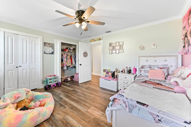 bedroom featuring ceiling fan, wood-type flooring, ornamental molding, and two closets