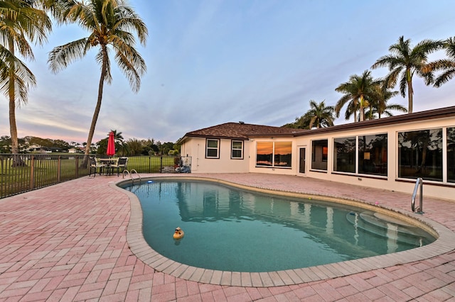 pool at dusk featuring a patio area