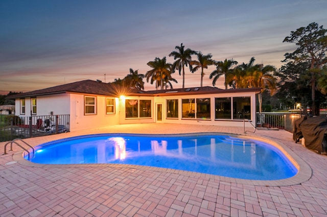 pool at dusk featuring a patio