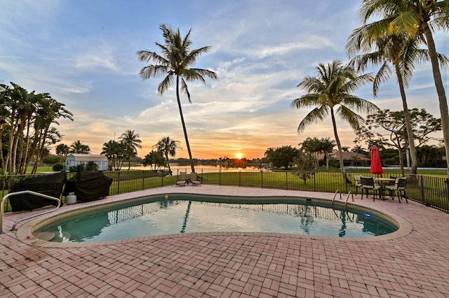 pool at dusk with a yard and a patio