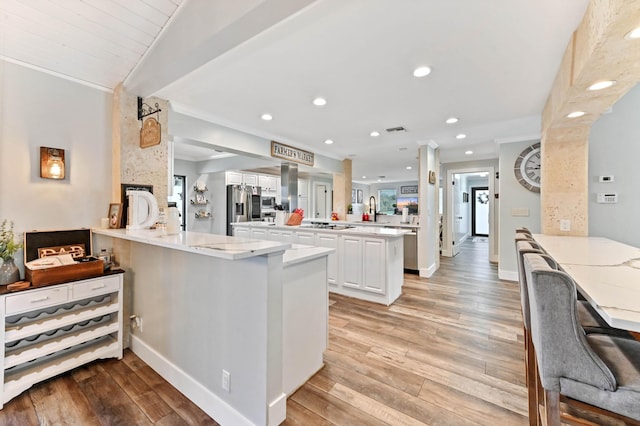 kitchen featuring kitchen peninsula, light stone countertops, and white cabinets