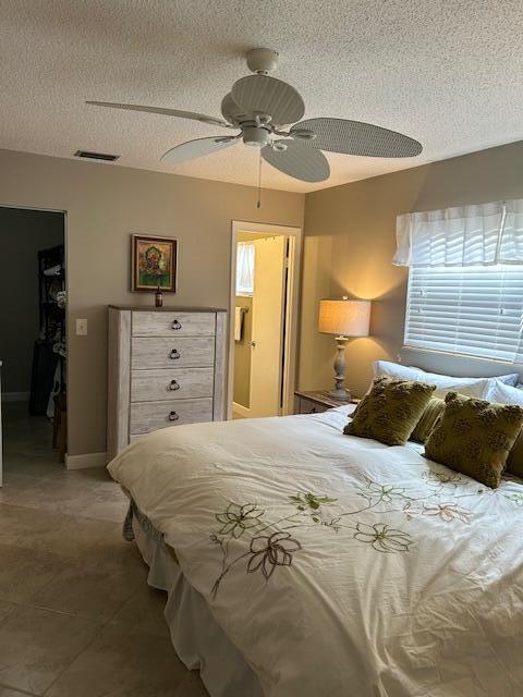 bedroom featuring a textured ceiling, a closet, ceiling fan, and a spacious closet