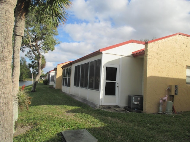 view of side of property with central AC, a sunroom, and a lawn